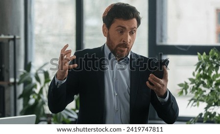 Angry furious businessman using phone in office loses online lottery losing bet on internet worried to bad result financial loss stressed upset man entrepreneur disappointed failure fails in business Royalty-Free Stock Photo #2419747811