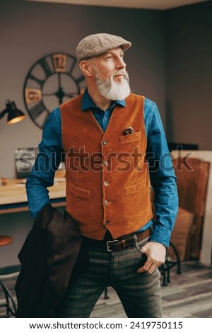 Indoor portrait of a mature hipster photographer man with a beautiful beard and very stylish look