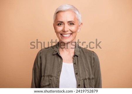 Portrait photo of optimistic mature age business woman wearing casual khaki shirt very positive isolated on beige color background