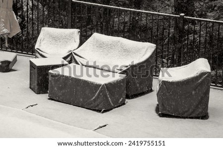 outdoor furniture covered in snow during winter poolside (protective coverings over chair, couch, table alongside the pool) off season storage, protection during blizzard storm Royalty-Free Stock Photo #2419755151