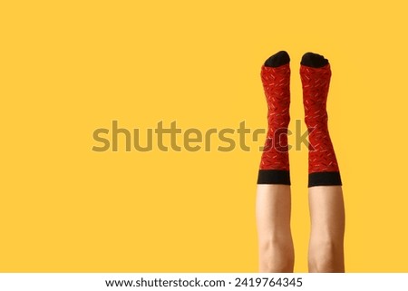 Legs of young woman in red socks on yellow background