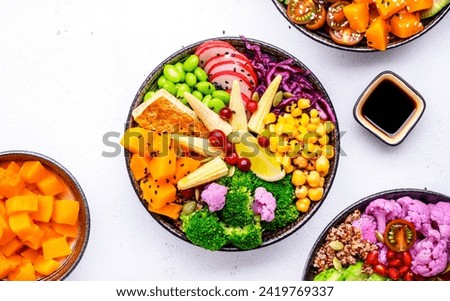 Vegan buddha bowls assortment with pumpkin, quinoa, tomatoes, spinach, avocado, radish, soybeans, edamame, tofu and seeds on white background, top view. Healthy menu, slow comfort vegetarian food