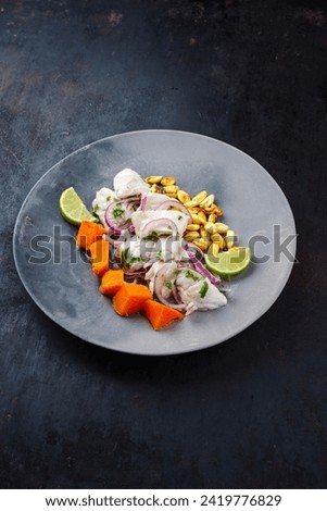 Traditional Peruvian gourmet ceviche sea bass filet piece with sweet potatoes and cancha marinated and served in lime sauce as close-up in a modern design plate 