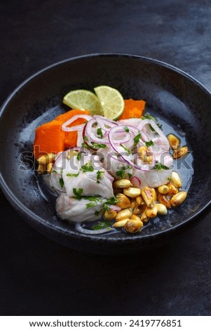 Traditional Peruvian gourmet ceviche sea bass filet piece with sweet potatoes and cancha marinated and served in lime sauce as close-up in a modern design bowl 