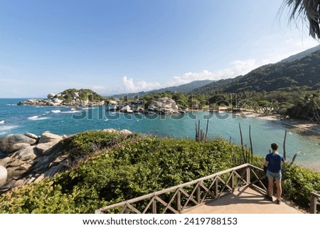 Young man enjoying the cabo san juan beach landscape from a viewpoint with rocky mountains and caribbean turquoise sea at background