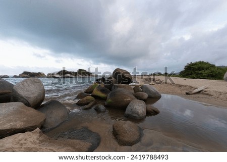 rocky small peak in middle of a delta between a small river and caribbean sea in arrecife beach located into colombian tayrona park