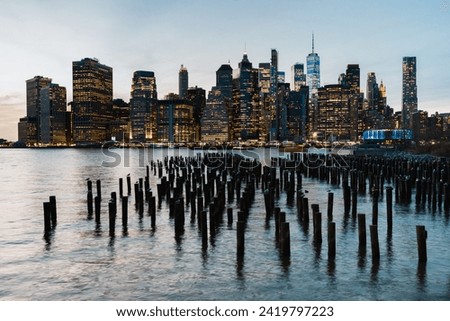 View of the Manhattan skyline in the evening, seen from the Brooklyn Pier with wooden breakwaters in the foreground