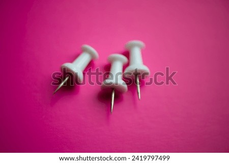 Three white pushpins on pink, close -up. Business concept.