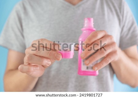 Man drinking antacid syrup to treat gastritis, stomach ulcer, heartburn, acid indigestion from measuring cup. Taking medicine, health care, pharmacy and treatment concept. Selective focus Royalty-Free Stock Photo #2419801727