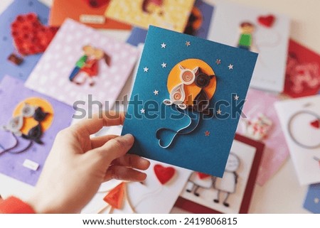 Hand holding quilling card with cute cats in love among the moon and stars. Love concept. Happy valentine day, dating,romantic or wedding. making greeting cards. Hand made of paper quilling technique