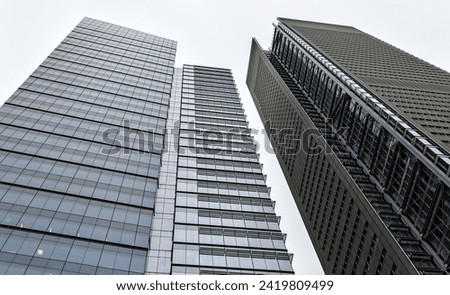 tall skyscraper buildings looking up with overcast dark cloudy sky in the background (urban skyline towers) glass windows, detail, high rise commercial office towers