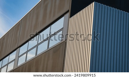 Italian Landscape: Modern office building, illuminated by daylight. Soberly coloured facade of glass, aluminium and steel, Backdrop of a clear azure sky. Focus of contemporary industrial architecture