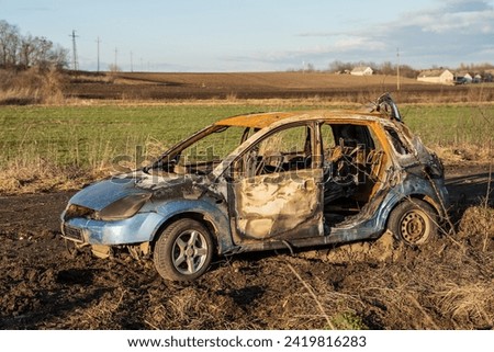 A burned car wreck near to highway Royalty-Free Stock Photo #2419816283