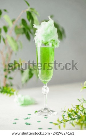 Glass of green champagne with cotton candy on the table. St. Patrick's Day Concept