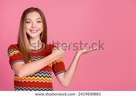 Photo of nice positive girl indicate finger arm palm hold empty space isolated on pink color background
