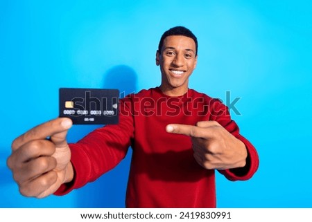 Photo of funny cheerful man wear red trendy sweater hold bank card recommend online cashless payment isolated on blue color background