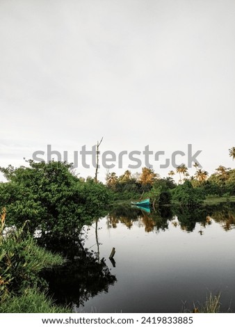 boat anchored middle of calm lake surrounded by green forest 