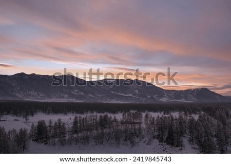 Cold snowy mountain landscape at sunset. Panoramic view of snowy mountain peaks and slopes of North Chuyskiy ridge at sunset. Russia, Siberia, Altai mountains. 