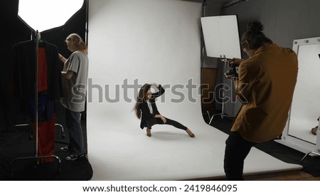 Backstage of model and professional team in the studio. Full shot attractive female model in suit posing on the floor, photographer taking pictures.