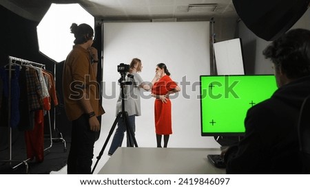 Backstage of model and professional team in the studio. Stylist assistant fixing look of model on set, editor at the desktop chroma key green screen.