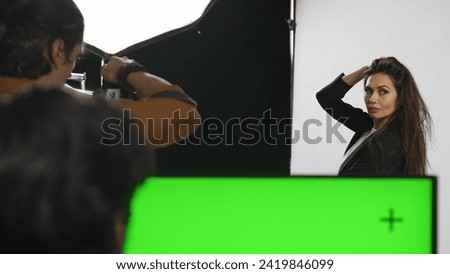 Backstage of model and professional team in the studio. Close up of model in suit posing for photographer, editor at chroma key green screen monitor.