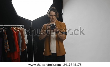 Backstage of model and professional team in the studio. Full shot of man professional photographer holding cam and looking at the camera.