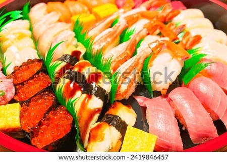 Hand-pressed nigirizushi with Japanese seafood, including anago Congridae, crab legs, shrimps, medium fatty Chūtoro tuna, and gunkanmaki filled with ikura red caviar sourced from salmonid fish roe. Royalty-Free Stock Photo #2419846457