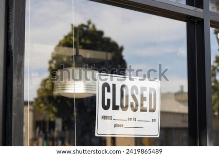 Closed sign attached to the storefront window with a suction cup hook.