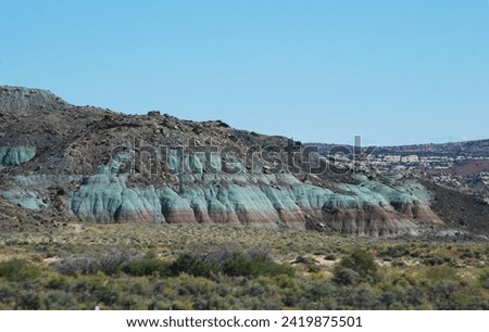 Layers of ancient rock outcroppings have a greenish cast along a hillside in southern Utah. The green layer represents the epoch of the dinosaurs and many fossils have been discovered in this layer.