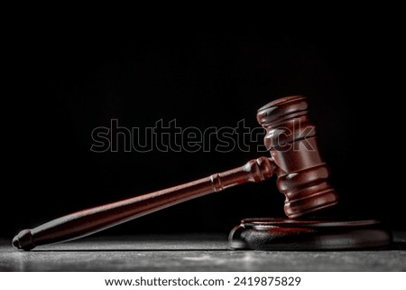 Wooden judge gavel and soundboard on the black background, close up