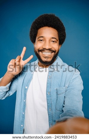 Cheerful Latin young man taking a selfie with a peace sign and a bright smile, the man showcases his fun-loving personality and a knack for creating engaging content for social media