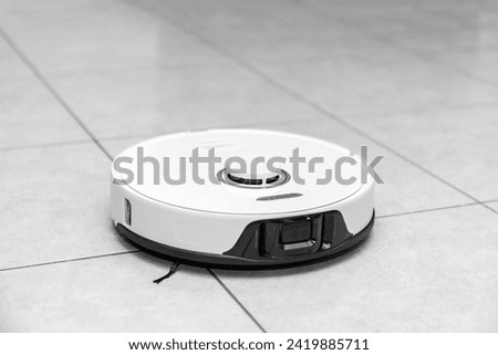 robot vacuum cleaner in modern smart home, robotic vacuum cleaner on tiles floor, Robot vacuum cleaner cleaning dust on tile floors. Modern smart cleaning technology housekeeping.	 Royalty-Free Stock Photo #2419885711