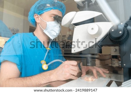 Embriologist putting sperm sample to examine under microscope or collecting in vitro cultured embryos for biopsy. Reproductive medicine clinic. Artificial insemination. Artificial conception clinic. Royalty-Free Stock Photo #2419889147