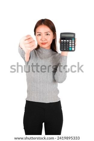 Annoyed young asian woman doing a thumb down gesture with her hand while holding a calculator against a white background