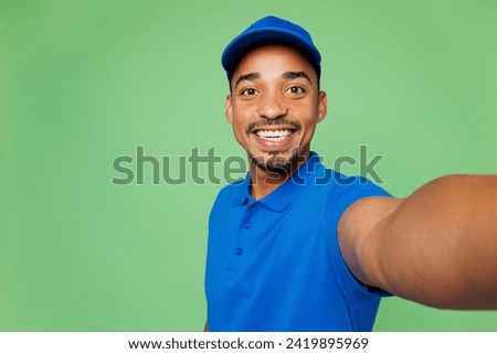 Close up professional delivery guy employee man wear blue cap t-shirt uniform workwear work as dealer courier do selfie shot on mobile cell phone isolated on plain green background. Service concept