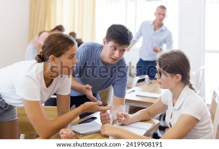 Focused teenagers working in small groups during lesson at college, discussing assignment given by teacher. Active learning concept Royalty-Free Stock Photo #2419908191