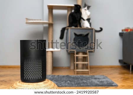 air purifier in the area with pets or cat. Air Pollution Concept. Air purifier, filters out invisible viruses, allergens or pollutants in the house on a cat tree background. Cute cat and Air purifier Royalty-Free Stock Photo #2419920587