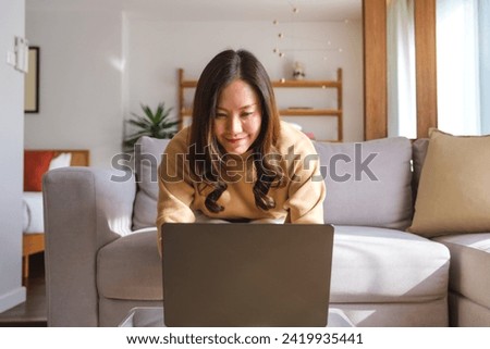 Portrait image of a young woman working on laptop computer at home