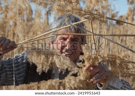 A man hides in the thickets of marsh grass reeds
