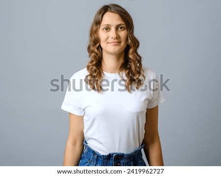 Happy successful woman in casual outfit smiling at camera and looking confident against gray background Royalty-Free Stock Photo #2419962727