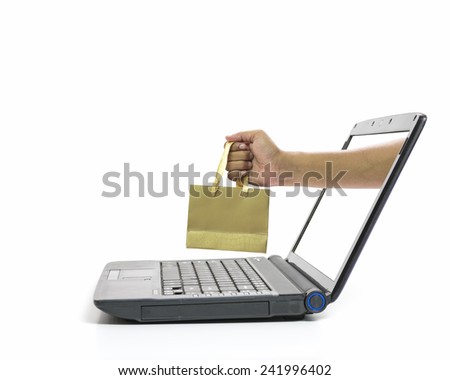 Hand come out from laptop screen holding shopping bag. On line business concept