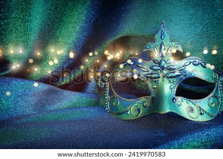 Photo of elegant and delicate Venetian mask over blue and green dark background