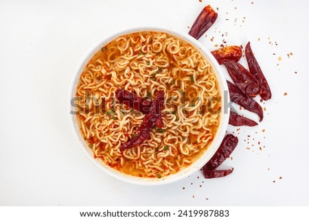 spicy instant noodles or ramen with dried chili on white backdrop with copy space. Flat lay, top view.