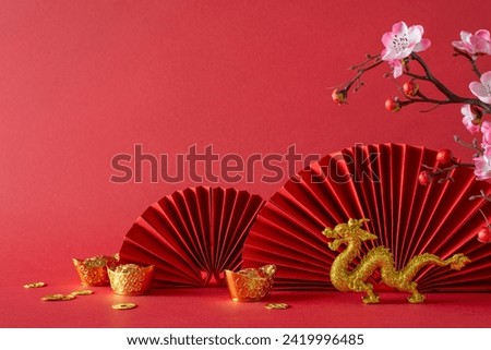 Prosperous composition: Side view of a table adorned with feng shui essentials, gold coins, dragon, sakura blossoms, and fans. A red background offers ample space for text or advertising