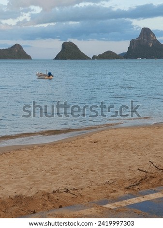 Golden yellow sand and blue-green sea, islands, mountains, grass, and small fishing boats, together it is a very beautiful picture.