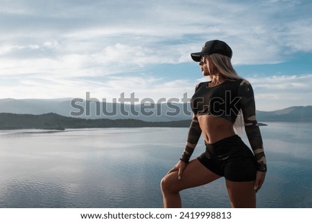 Fitness girl posing on the rocks overlooking the lake and sunset