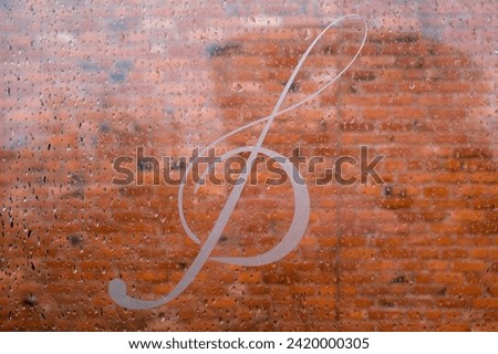 Treble clef on the background of a brick wall. Raindrops on glass. Rainy weather.