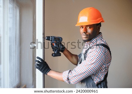 Close-up Of Young African Handyman In Uniform Installing Window.