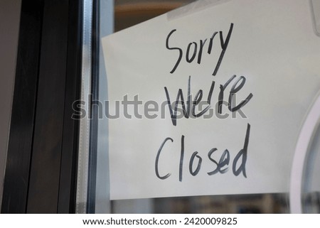 "Sorry We're Closed." Hand-written signage on the door at a small business.
