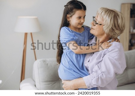 A nice girl and her grandmother enjoy sunny morning. Good time at home.